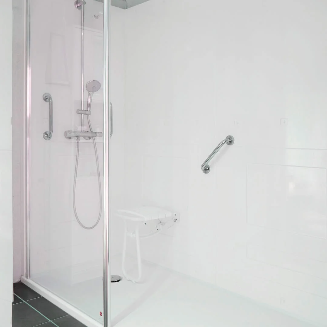 Douche senior blanche avec siège rabattable et barres d’appui à Charleroi